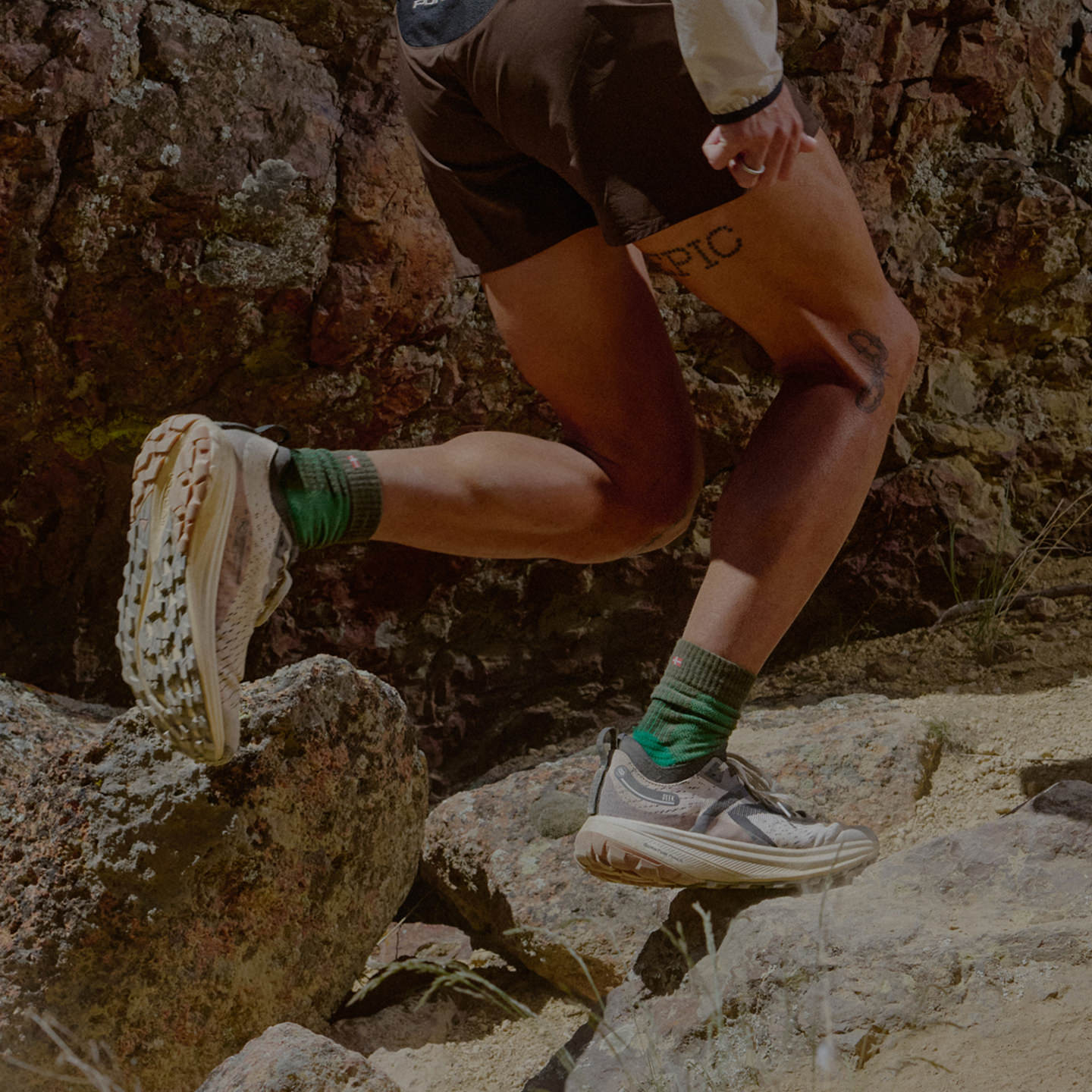 Waist-down shot of man wearing Keen Seek running shoes and traveling across rocky terrain