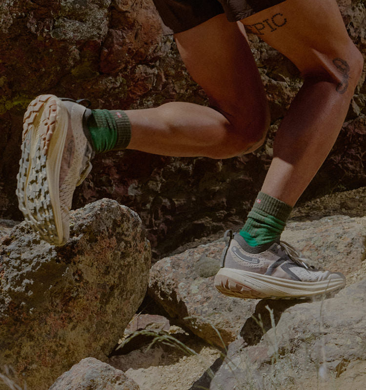 Waist-down shot of man wearing Keen Seek running shoes and traveling across rocky terrain