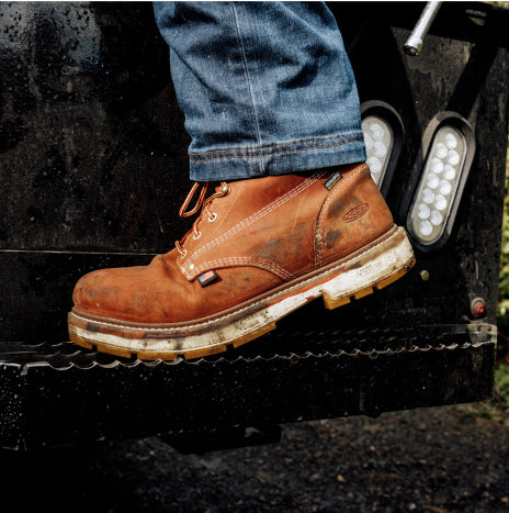 Close-up image of Liberty work boot on man wearing jeans stepping into a tractor