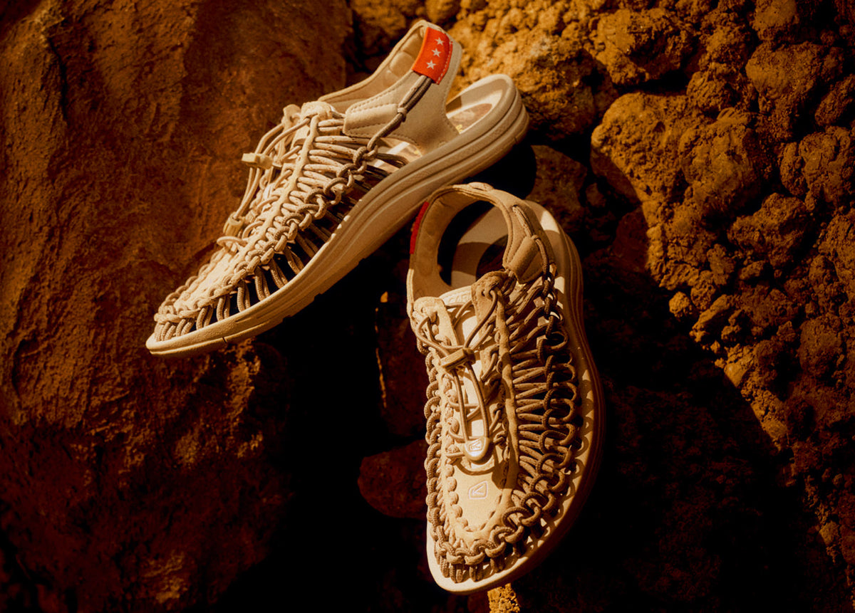 A close-up of off white shoes positioned on a rock, highlighting their natural color and unique string texture in an outdoor setting.
