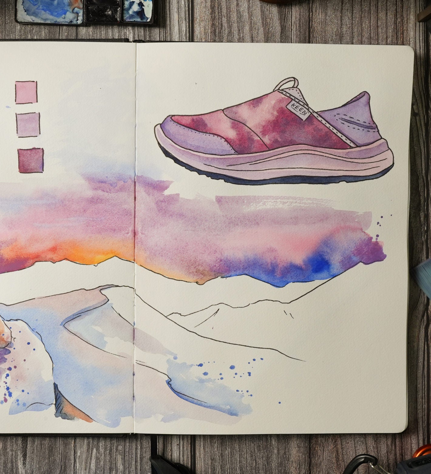 Watercolor sketch of a pair of shoes and mountains resting on a wooden table, showcasing soft colors and artistic details.