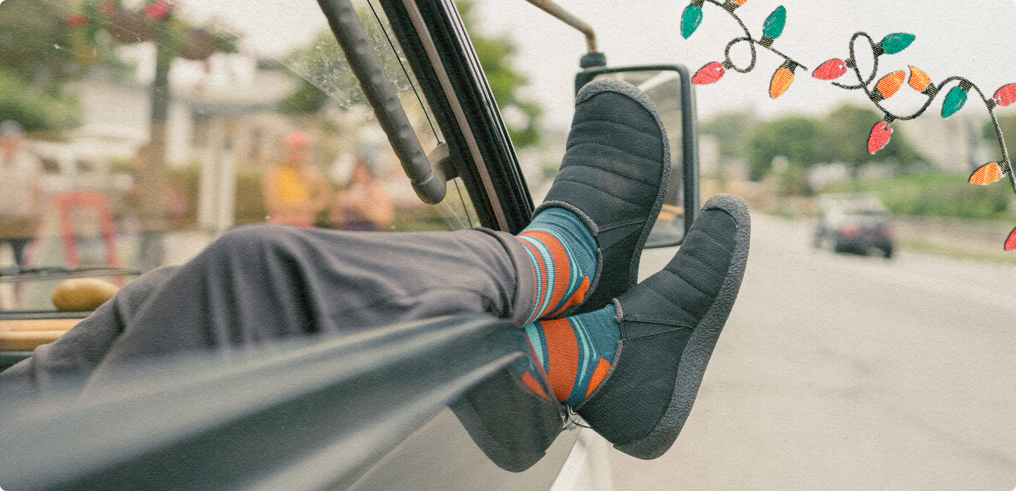 Man resting his legs out of van window while wearing cozy Howser slippers and festive socks. 