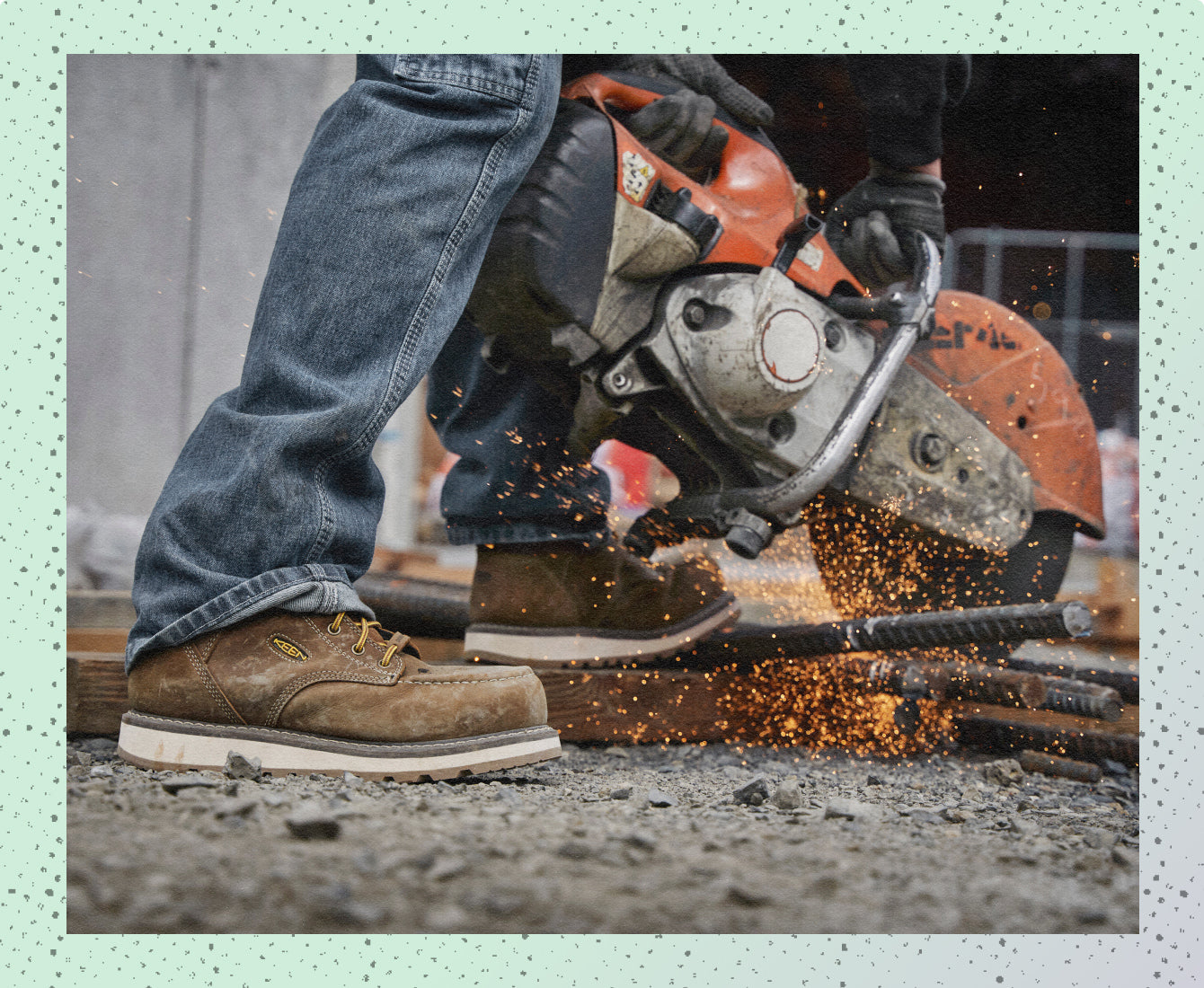 Knee-down shot of man in jeans wearing brown leather work boots while operating a circular saw with sparks flying.