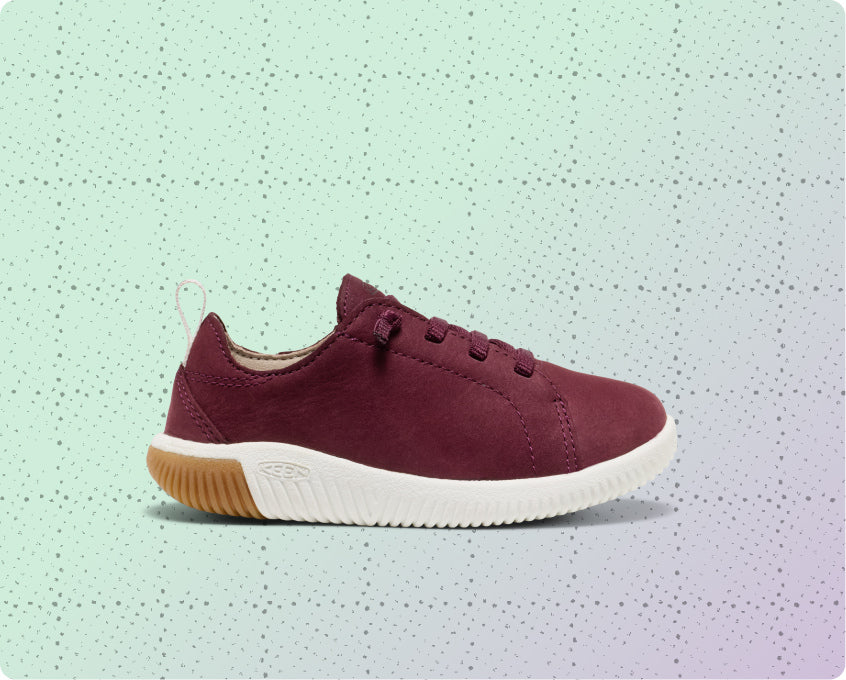 Kids' red leather, lightweight sneaker on a dotted grid wrapping-paper background.