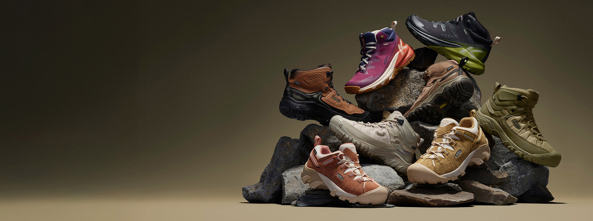 Various colored shoes from the KEEN Targhee collection stacked on rocks, highlighting their diverse styles and designs.