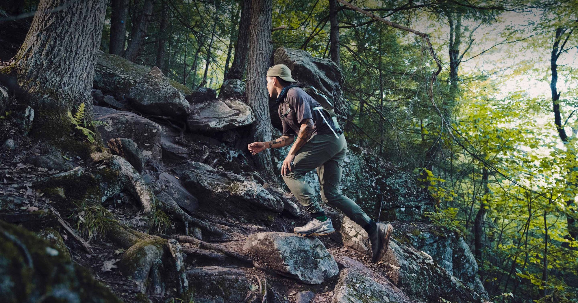  A man hikes up a rocky trail in the woods, wearing Targhee Apex shoes for support and traction.