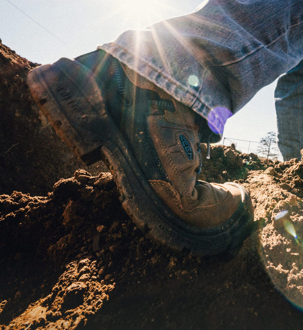 Man on dirt lot wearing Targhee IV Work boots while trudging through mud.