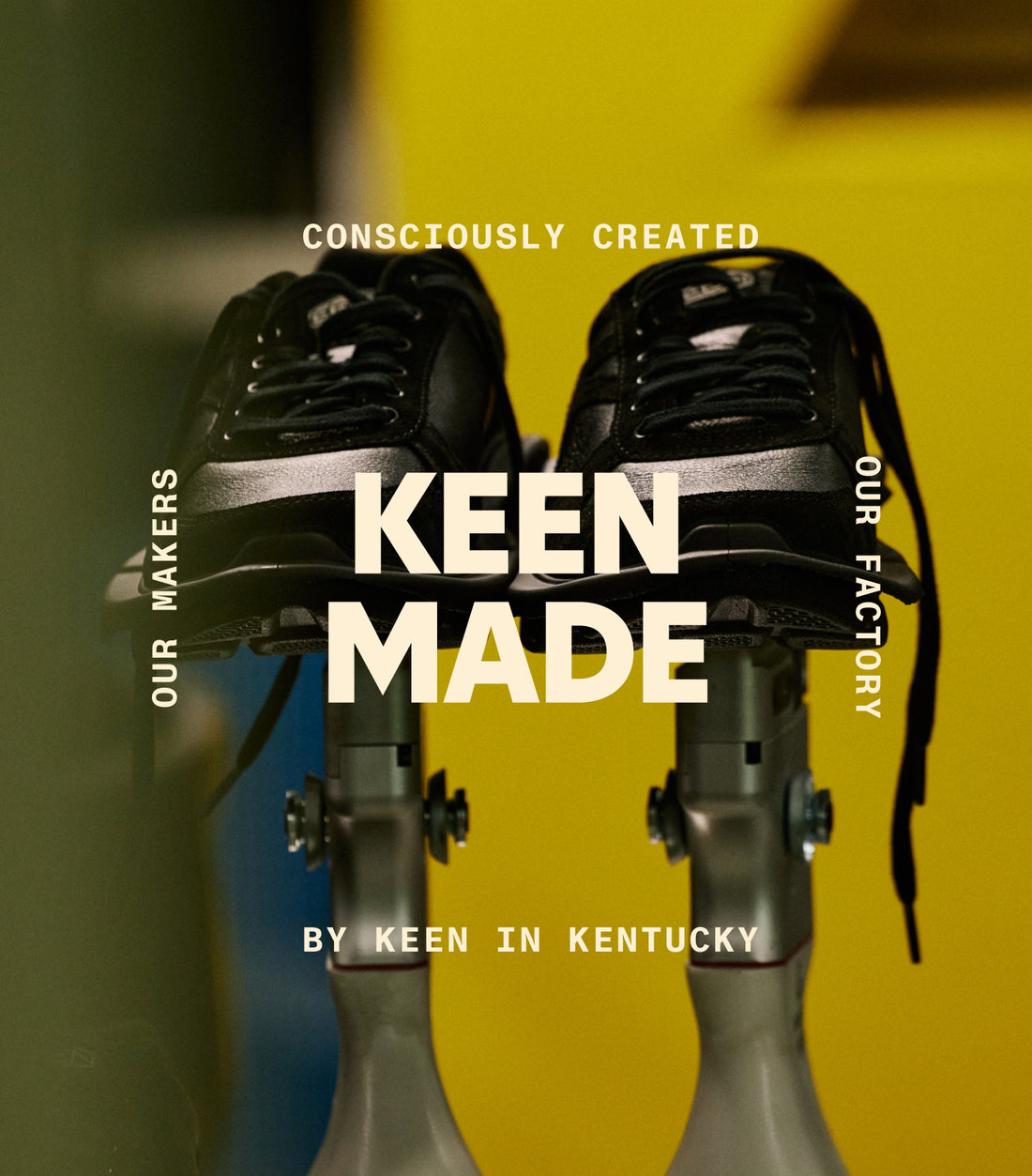 A pair of black shoes being held by factory machinery. Embedded with text that reads "KEEN MADE. Consciously Created. Our Makers. Our Factory. By KEEN in Kentucky."