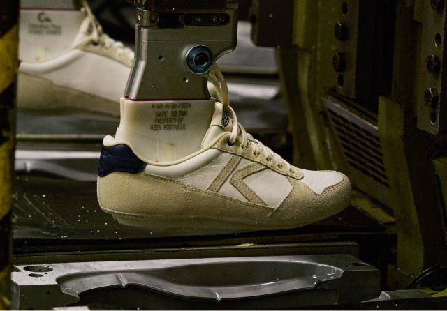 A machine holding the upper part of a shoe, in motion, showing the attachment of the sole using KEEN Fusion technology.