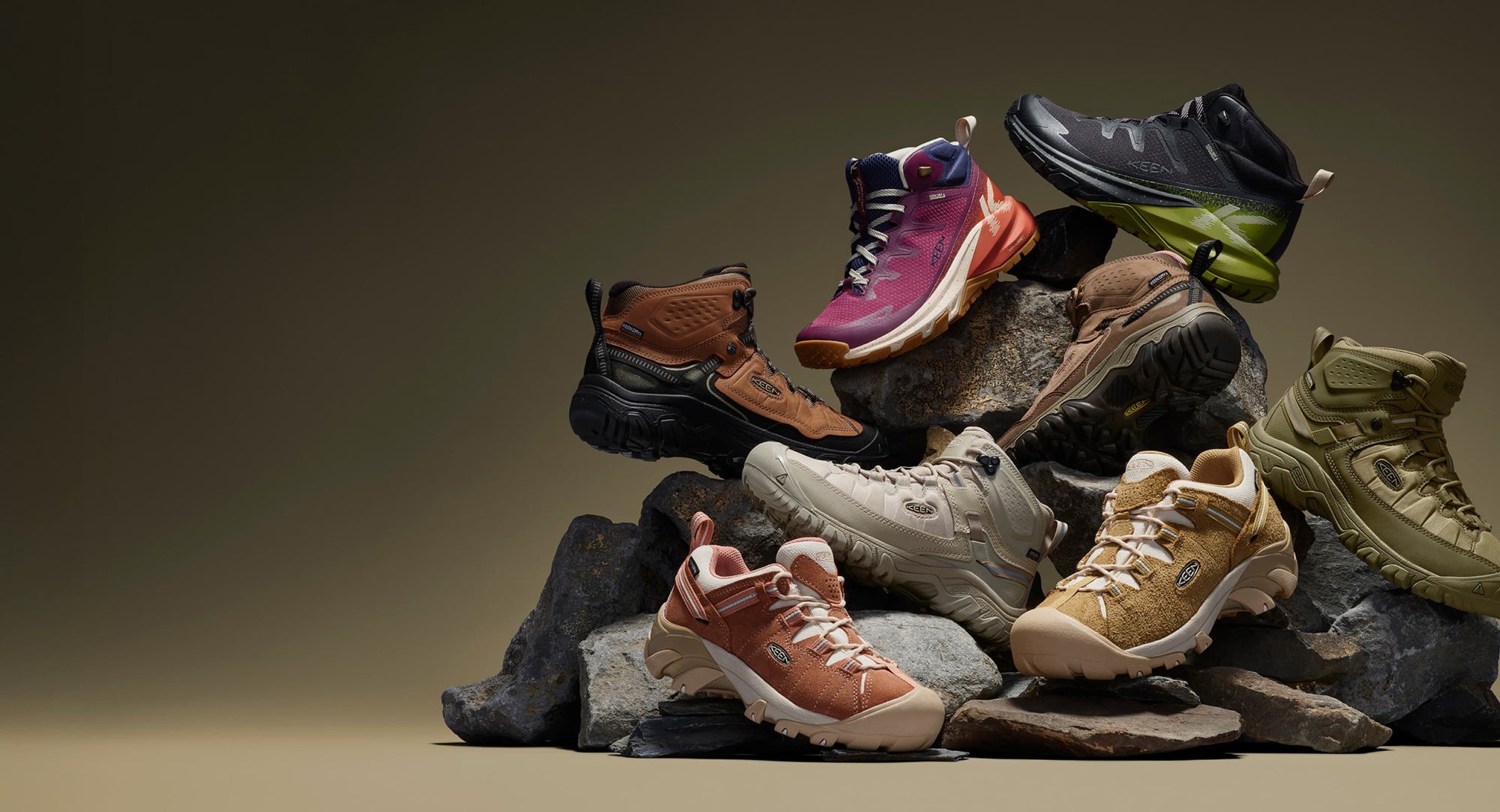 Various colored shoes from the KEEN Targhee collection stacked on rocks, highlighting their diverse styles and designs.