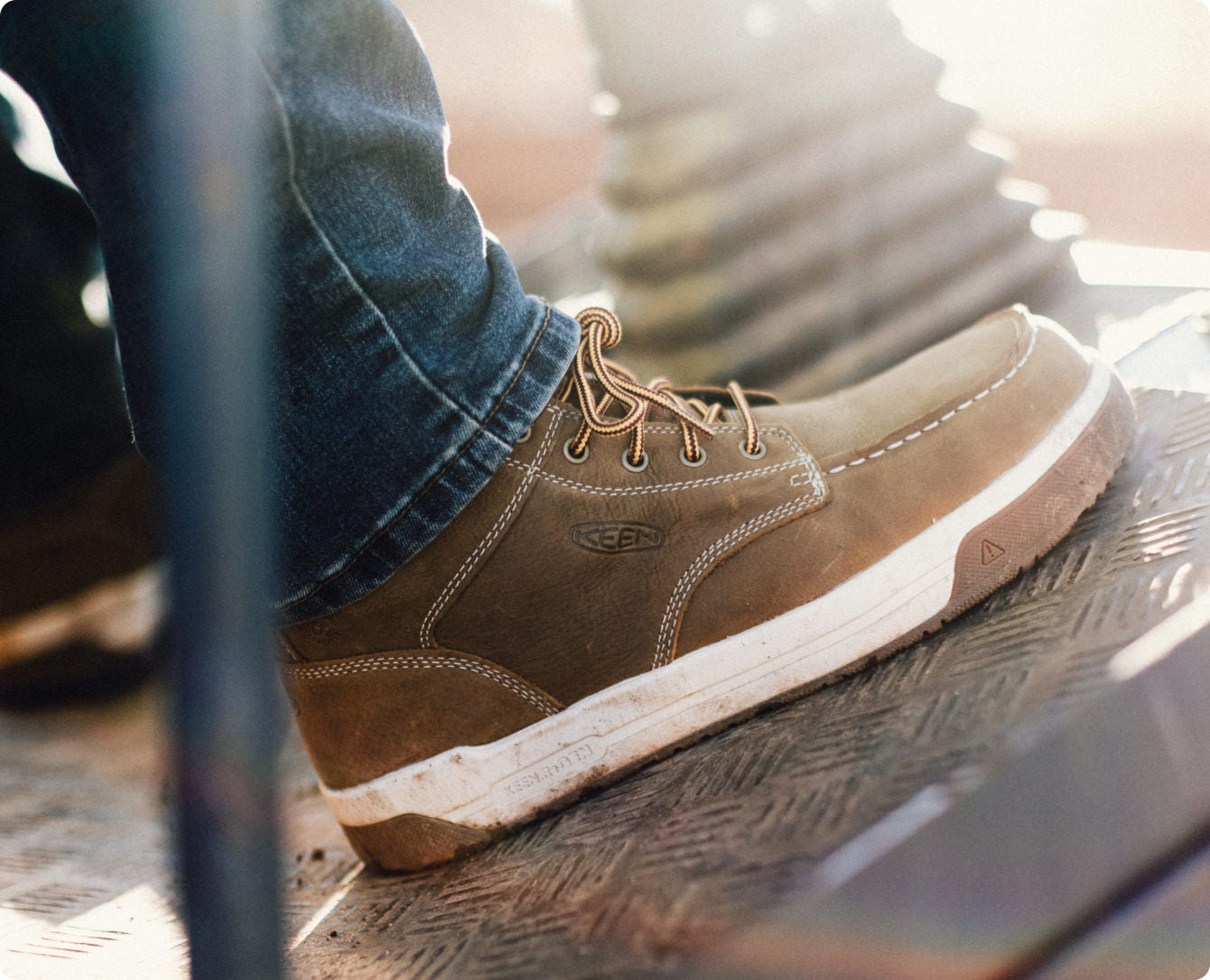 Man wearing the leather, brown Gibson work boot in an industrial setting. 