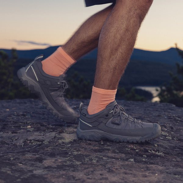Knee-down shot of a man wearing bright orange crew socks and Targhee EXP waterproof hiking shoes. 