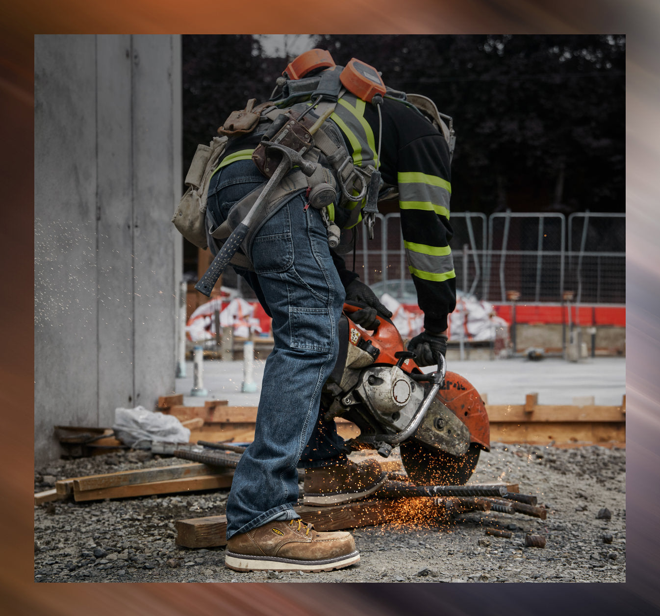 A man in construction attire using a circular saw on metal rods while wearing San Jose work boots. 