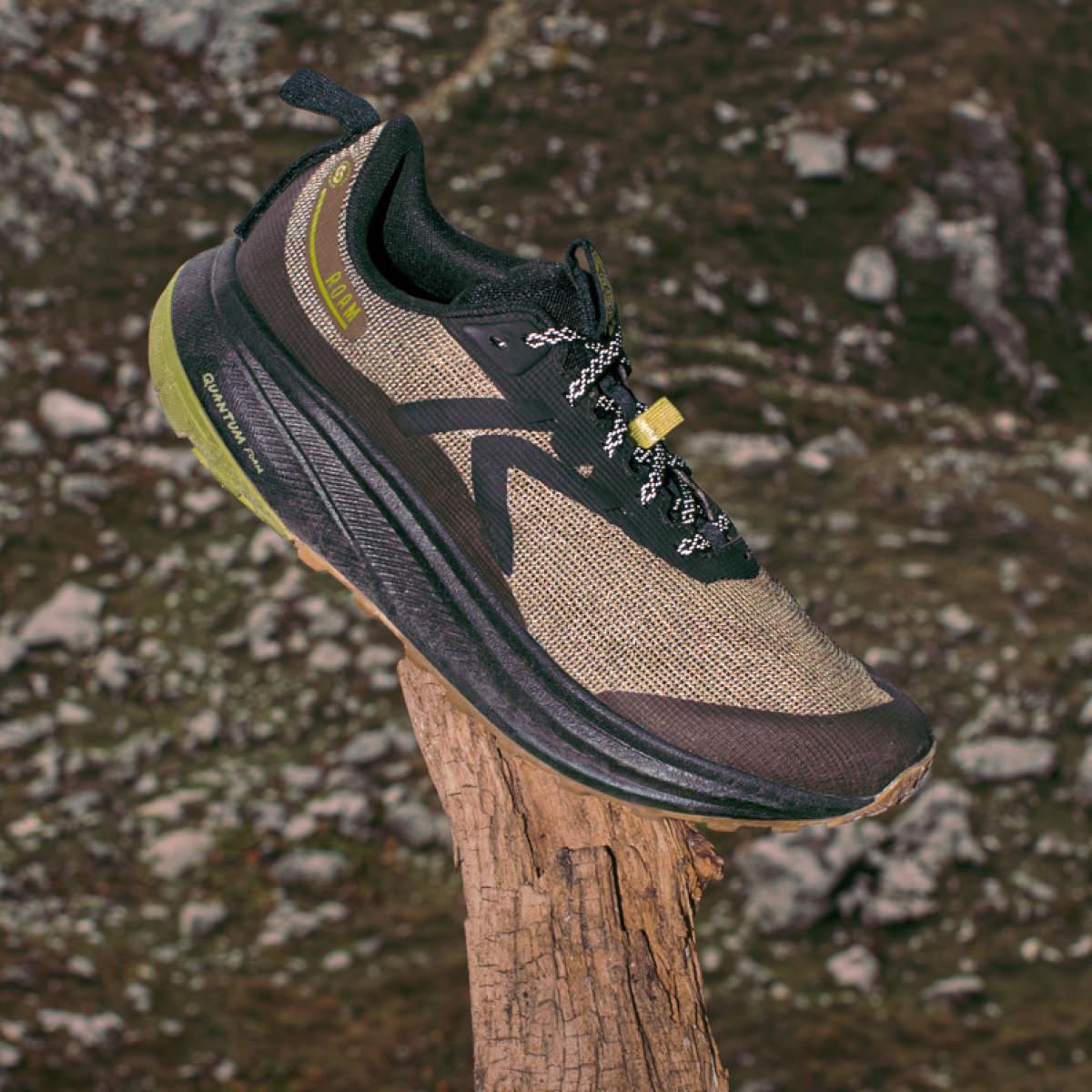 A single Men's Roam running shoe in Dark Olive and Golden Cypress sitting on a tree branch with a rocky valley below. 