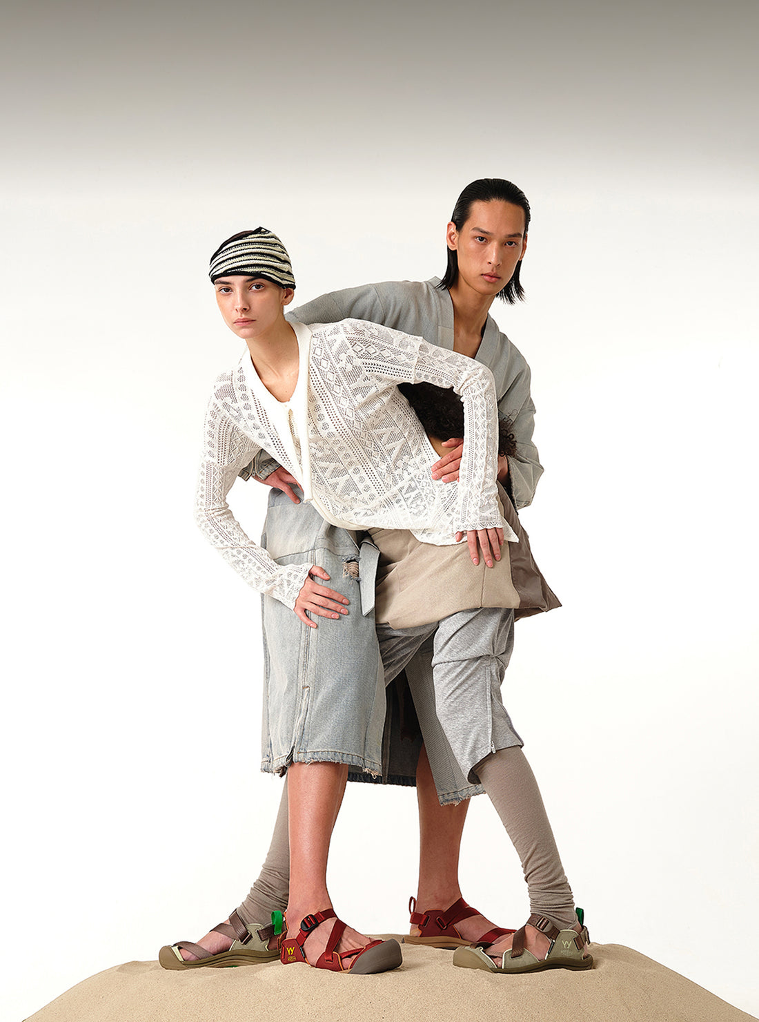 Two high fashion modules in a n intertwined pose wearing Open YY and KEEN collaboration sandals