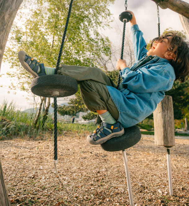 Child swinging on play structure with closed toe sandals