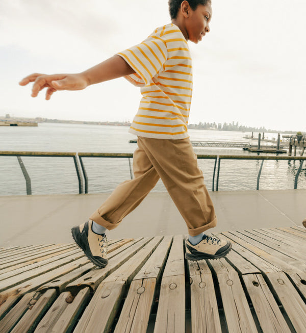 Child walking on a pier in KEEN Kids' jasper zionic sneakers.