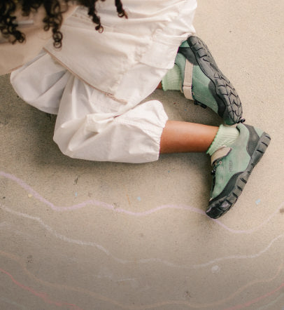 Kid drawing with sidewalk chalk wearing keen kids jasper sneakers.