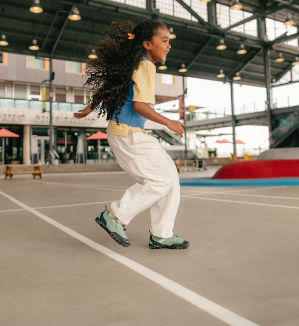 Girl running on pavement in keen kids jasper sneakers.