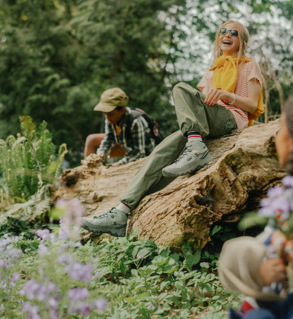 Big kid sitting on old log in the laughing in the forest wearing KEEN Kids' Targhee IV. 