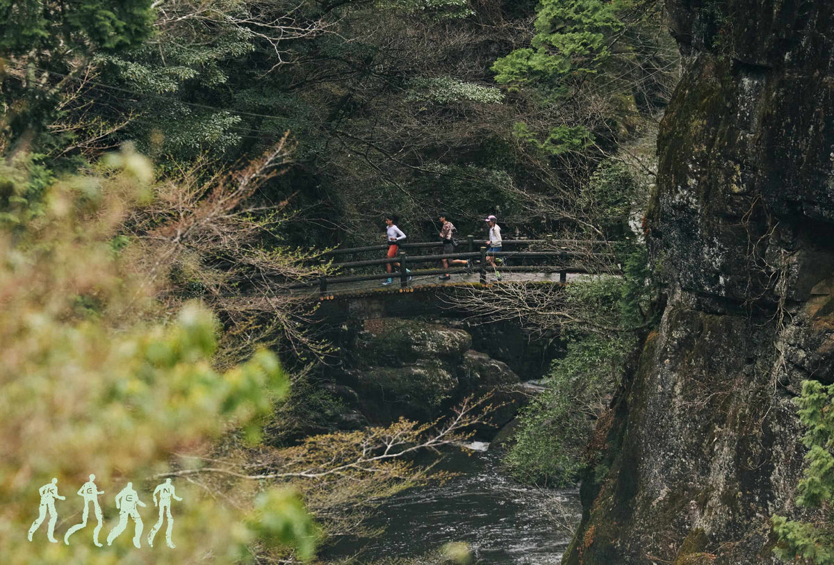Three People jogging over bridge in a wooded canyon