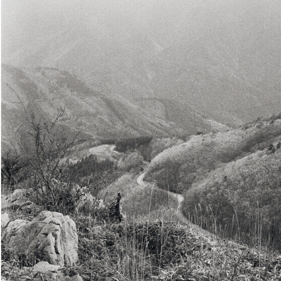 Black and white landscape image of mountain trail weaving into the distant valley canyon