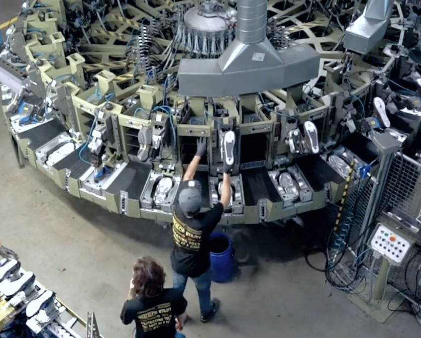 Overhead shot of a large, metal shoe-making machine at the KEEN factory.