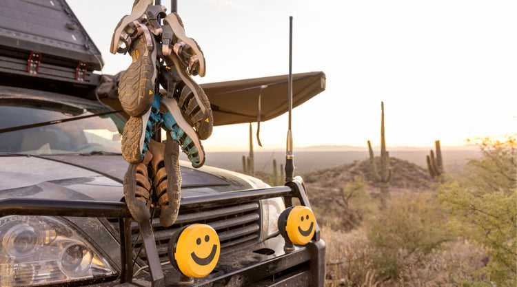 Four pairs of Newport snadlas hanging from car radio antenna in desert