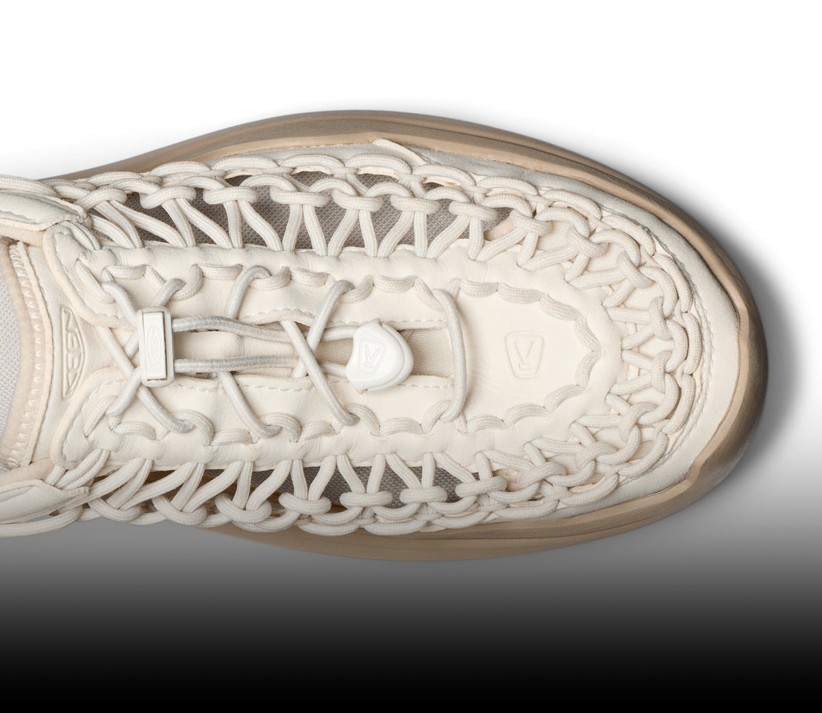 Top-down view of a cream UNEEK sandal highlighting the intricate interlocking cord design and bungee lace system.