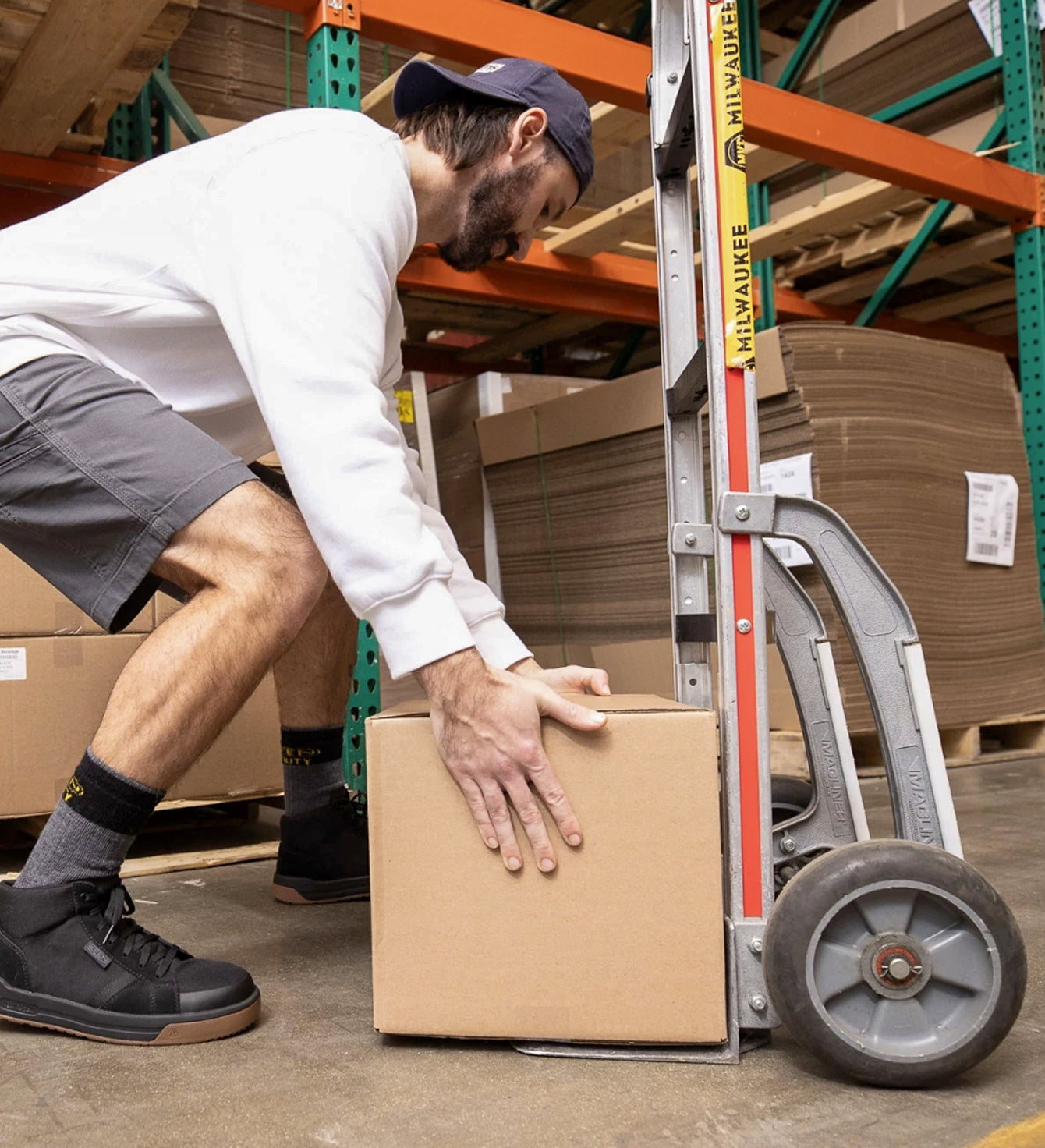 Man crouching down loading box onto dolly in a warehouse
