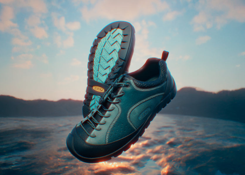 Product shot of dark-blue/green KEEN x Eastlogue Jasper Rocks sneakers with ocean background.