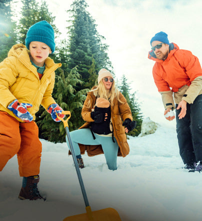 Family in snow playing with shovel and snowballs