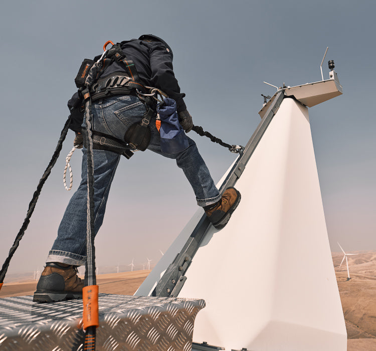 Worker standing on wind turbine above wheatfields