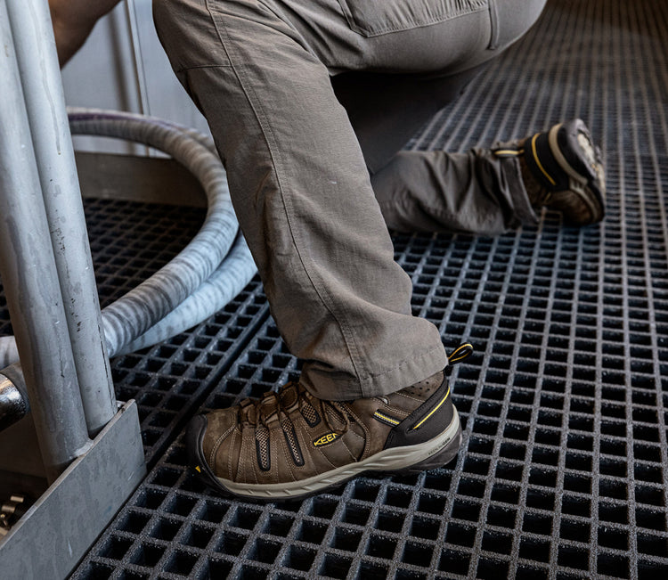 Man kneeling on metal grate wearing brown Flint II work shoes