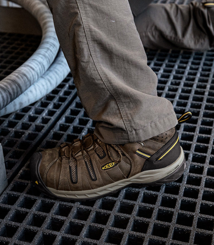 Man kneeling on metal grate wearing brown Flint II work shoes
