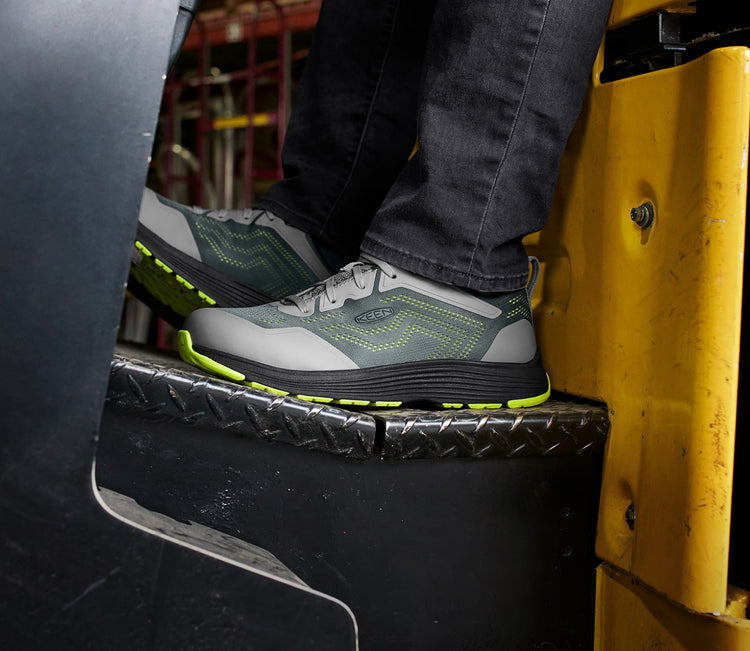 Close-up of Sparta 2 work sneaker on foot of man driving warehouse lift. 