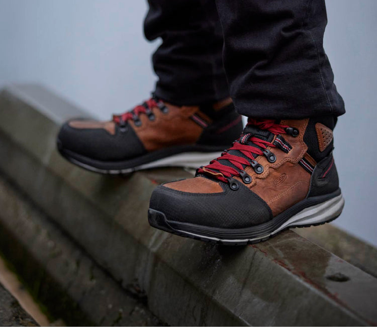 Man wearing red hook work boots standing on curb.