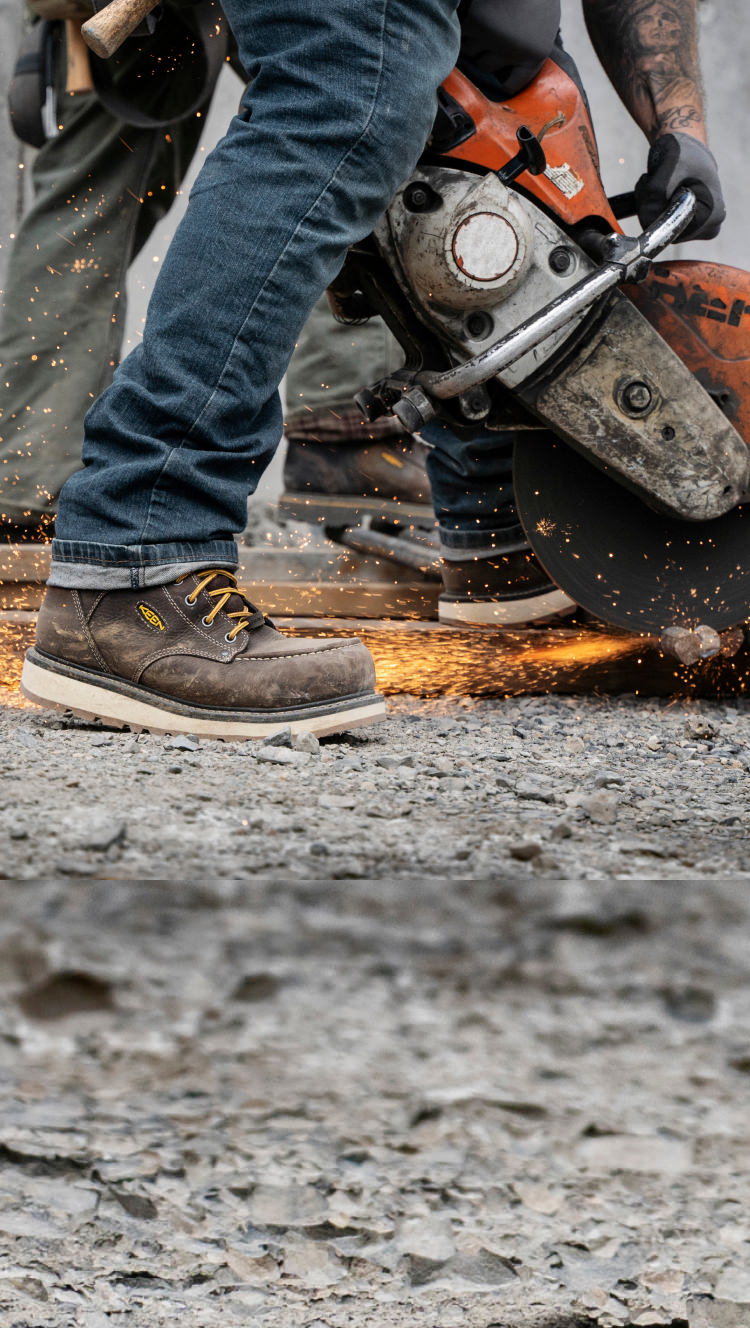 Knee down view of man wearing Cincinnati work boots and using a circular saw to cut metal 