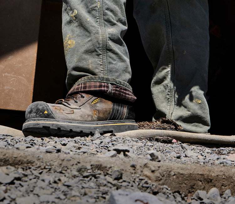 Knee down view of man wearing Abitibi II on gravel, muddy terrain.