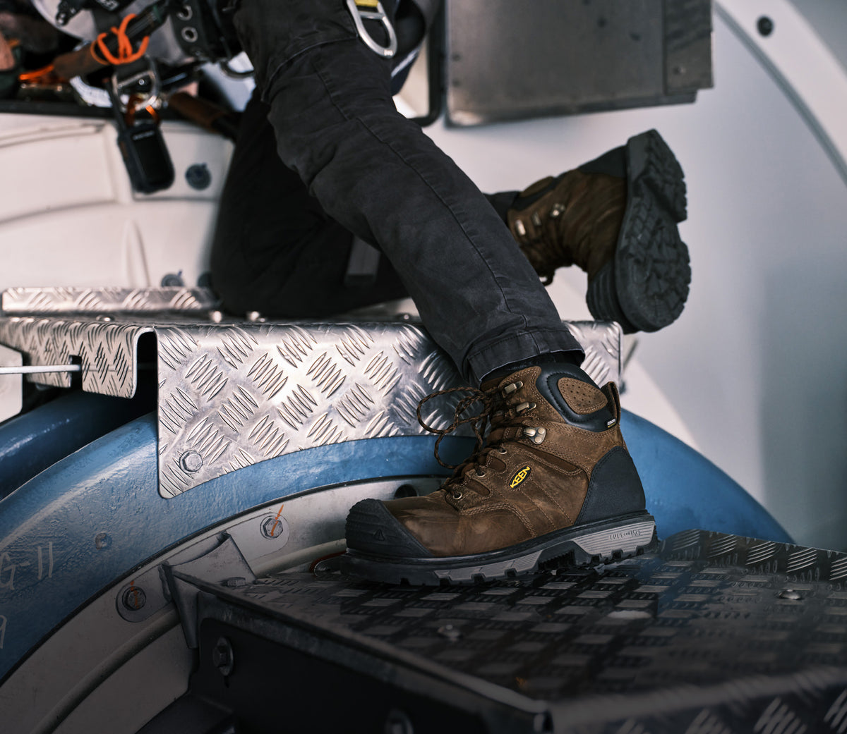 Waist down shot of a man in jeans and safety harness wearing Camden work boots and working on a metal structure 