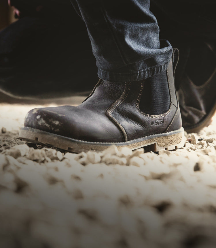 Knee-down shot of man wearing jeans and Seattle Romeo work-boots and walking on gravel 