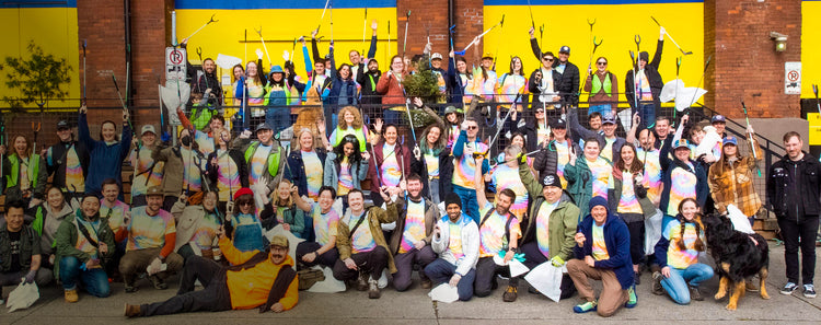 Keen Employees in tie-dye shirts posing iwith garbage-collecting supplies in front of Keen building