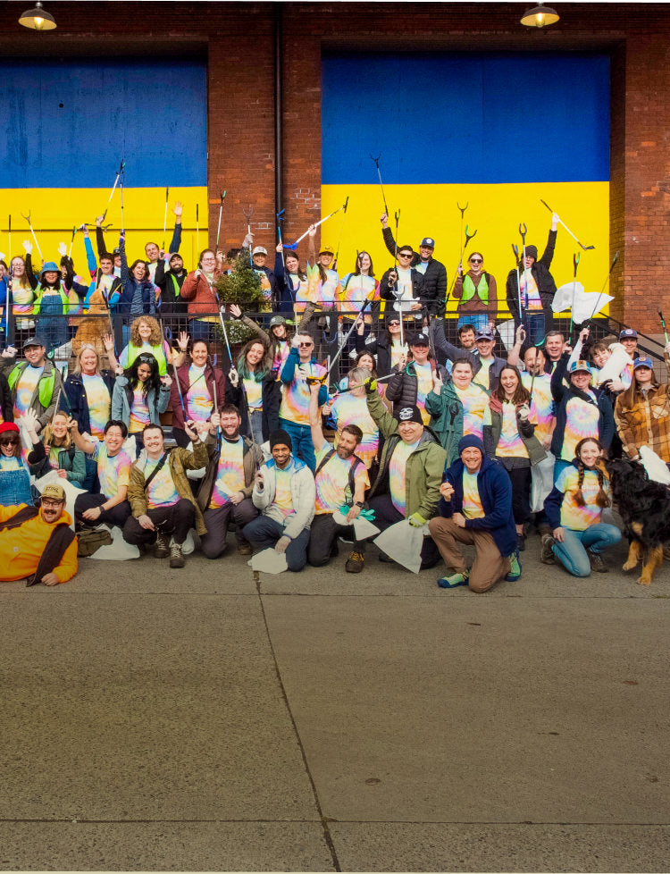 Keen Employees in tie-dye shirts posing iwith garbage-collecting supplies in front of Keen building