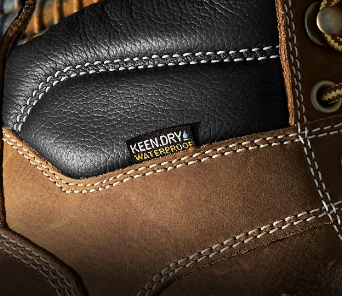 A close-up of a brown and black KEEN work boot featuring KEEN.DRY waterproof material.