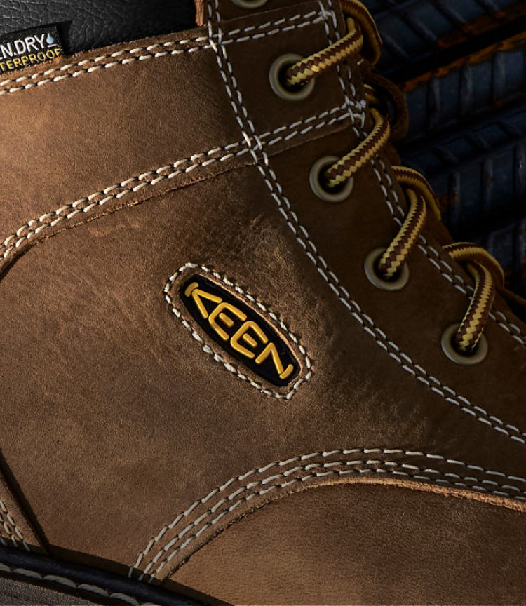 A close-up of the KEEN logo on a brown Cincinnati work boot.