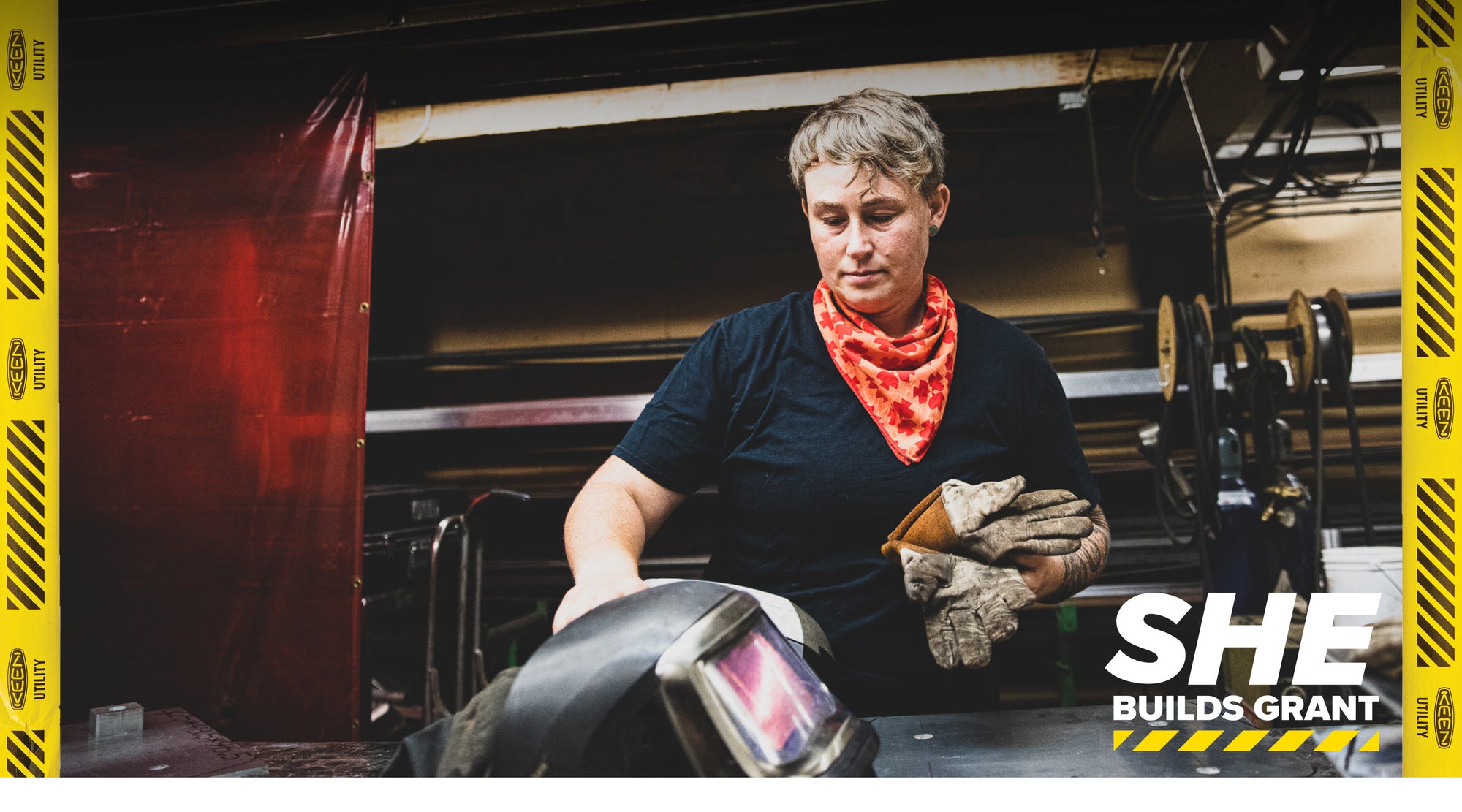 Woman welder holding her gloves in front of machinery 