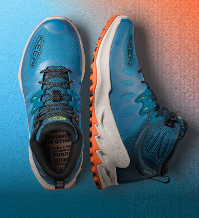 Closeup of blue and orange Zionic boots on gradient background