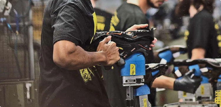 Man using blue handheld machine to mold a shoe in a factory