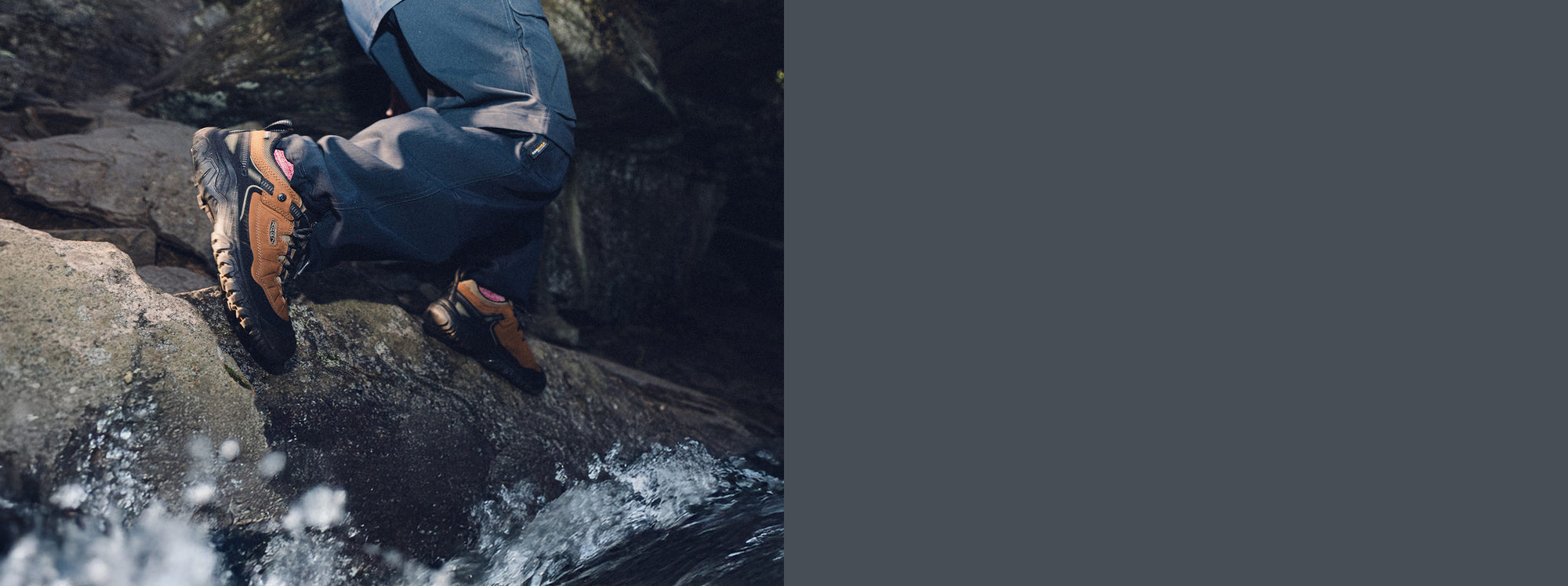 Man wearing waterproof Targhee IV hiking shoes and stepping across river rocks while water splashes his feet. 