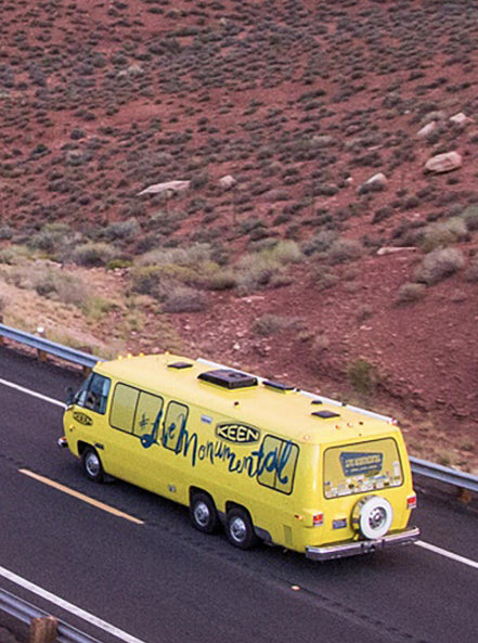Keen yellow bus driving through red desert landscape 